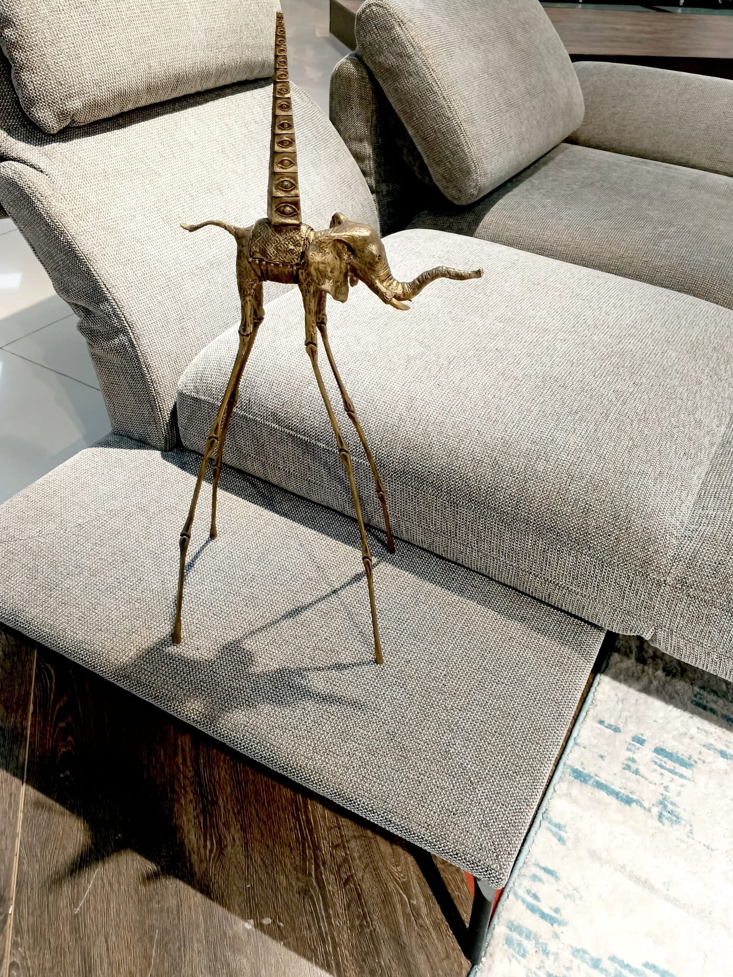 Золотая статуэтка слона Дали с пирамидой у дивана — акцент в гостиной в стиле Сальвадора Дали