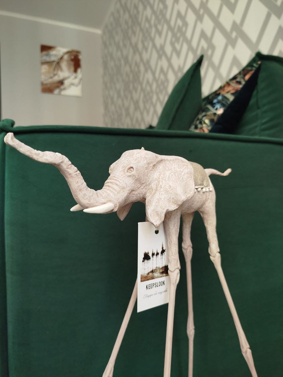 Белая статуэтка слона Дали у изумрудного дивана — контрастная композиция в стиле Сальвадора Дали