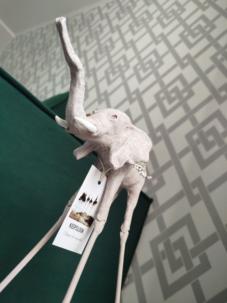 Белая статуэтка слона Дали у изумрудного дивана — контрастная композиция в стиле Сальвадора Дали