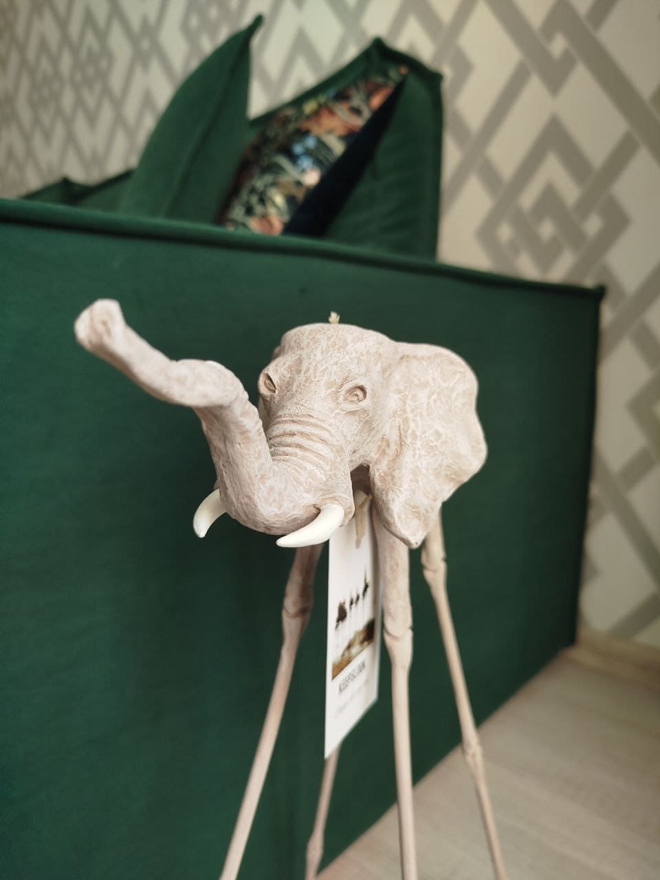 Белая статуэтка слона Дали у изумрудного дивана — контрастная композиция в стиле Сальвадора Дали
