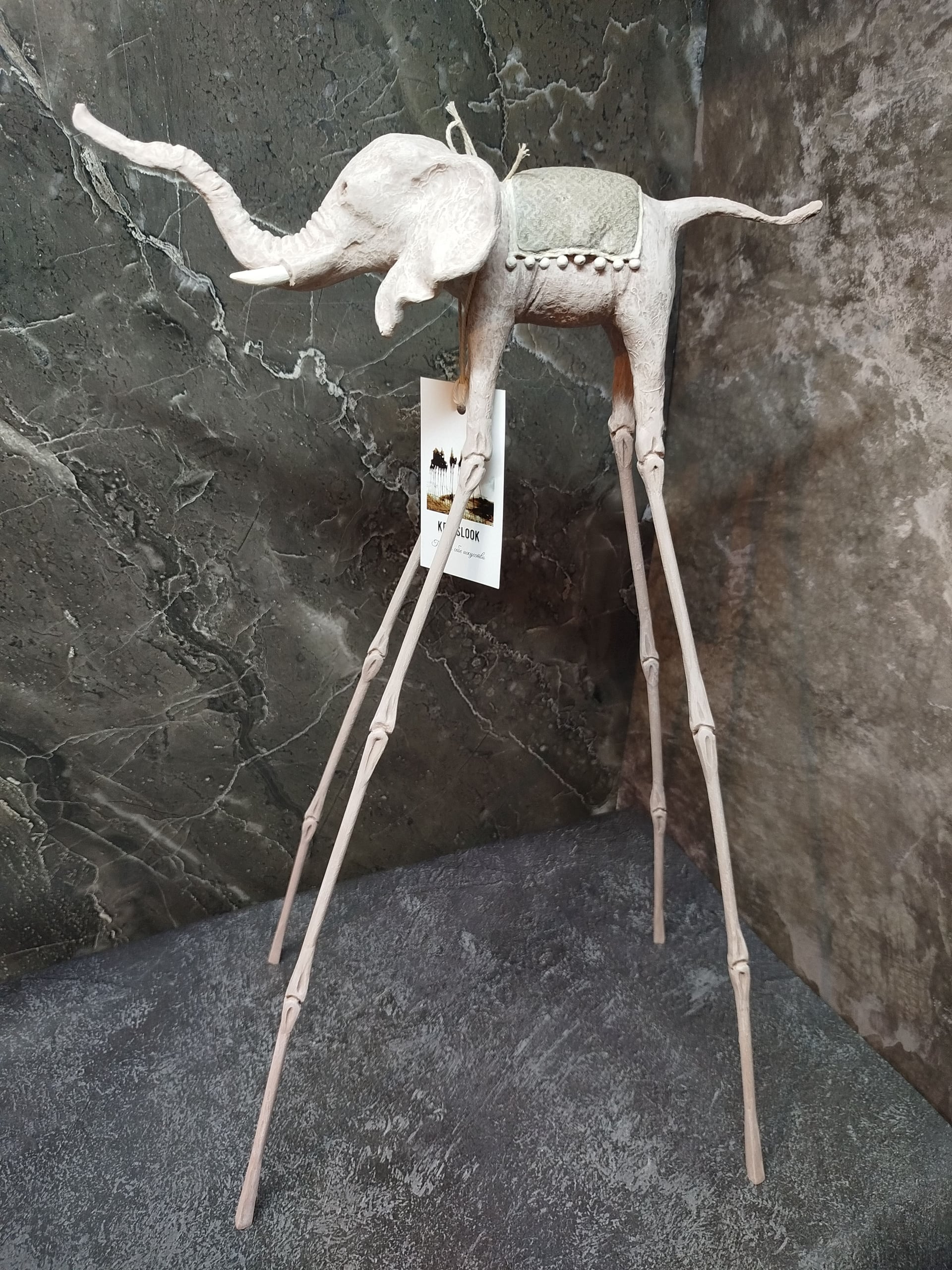 Белая статуэтка слона Дали у светлой стены — минималистичная подача авторского арта