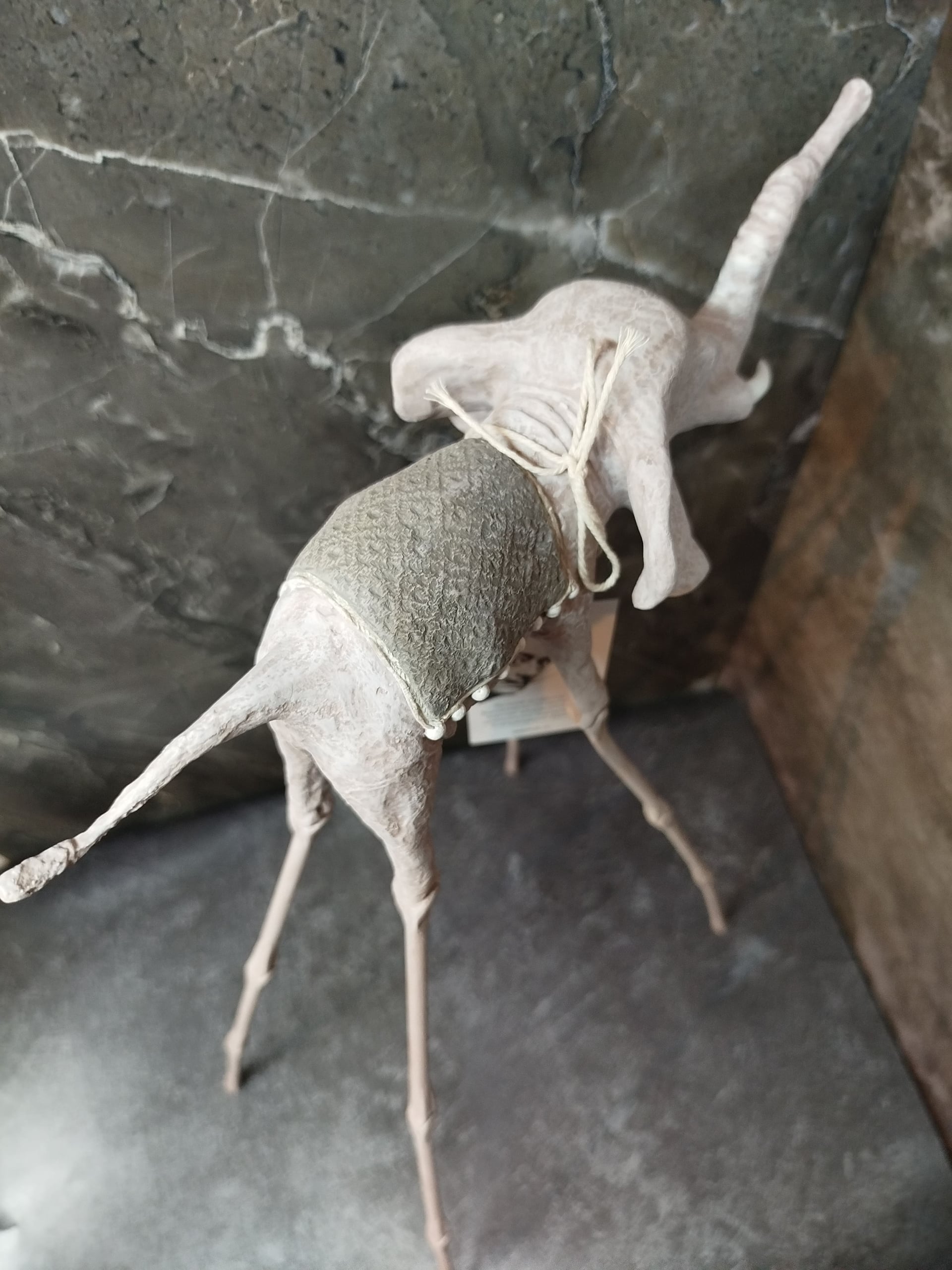 Белая статуэтка слона Дали у светлой стены — минималистичная подача авторского арта