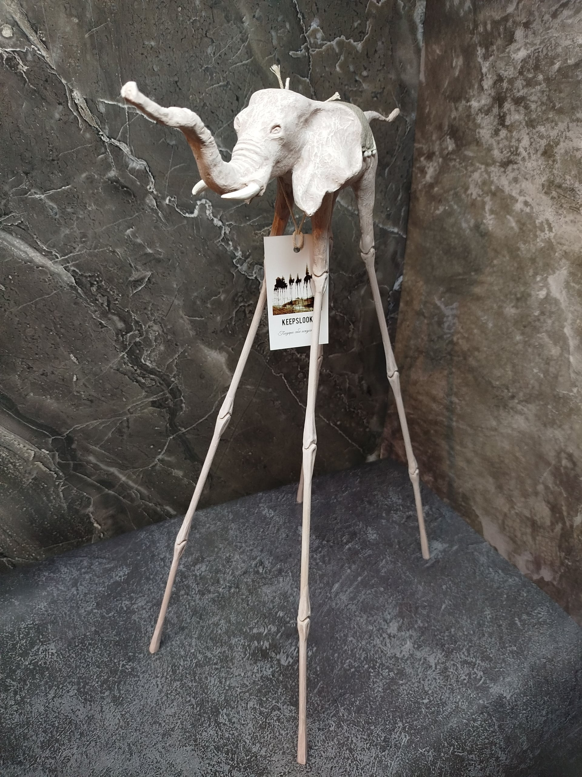 Белая статуэтка слона Дали у светлой стены — минималистичная подача авторского арта