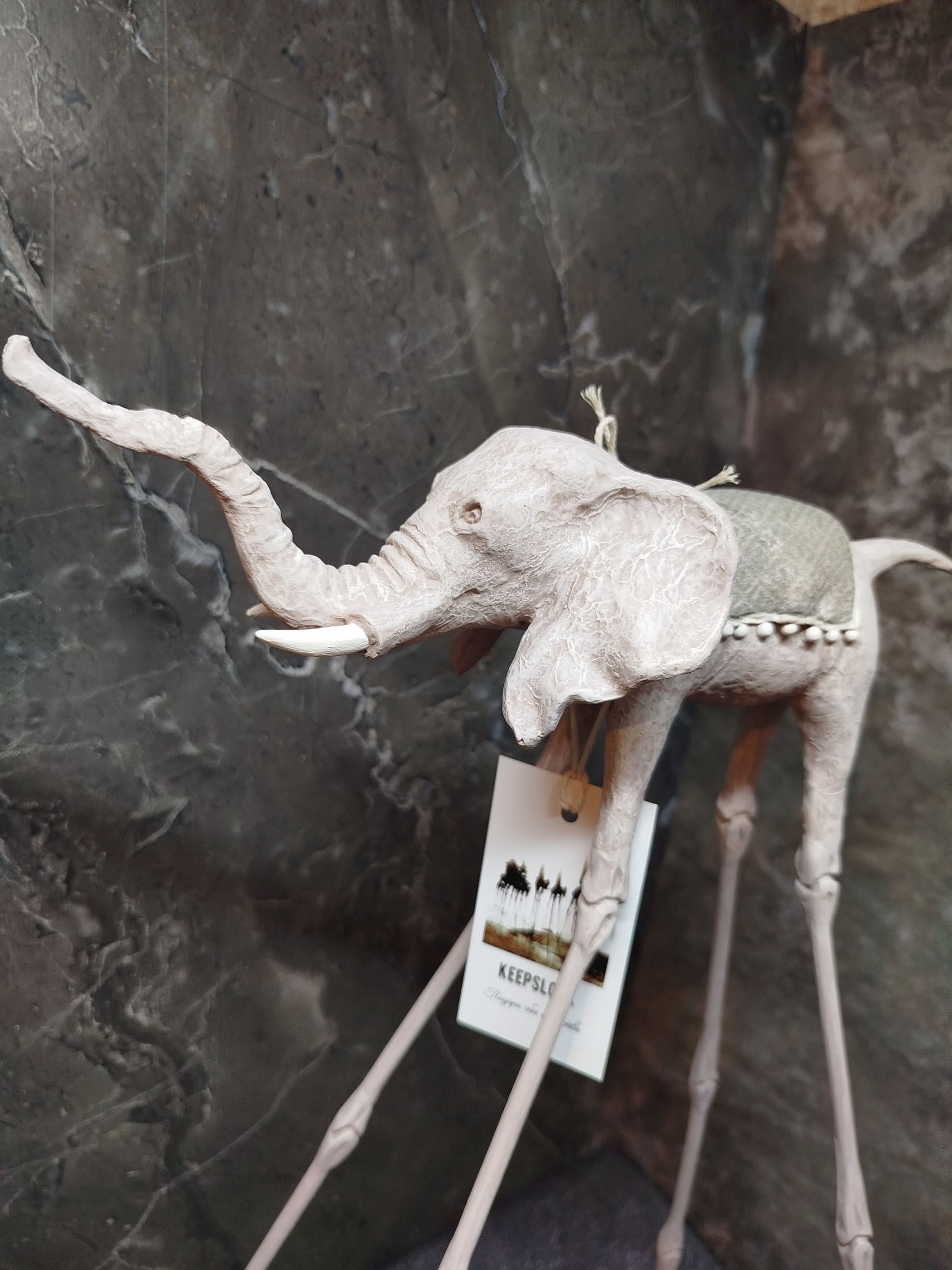 Белая статуэтка слона Дали у светлой стены — минималистичная подача авторского арта