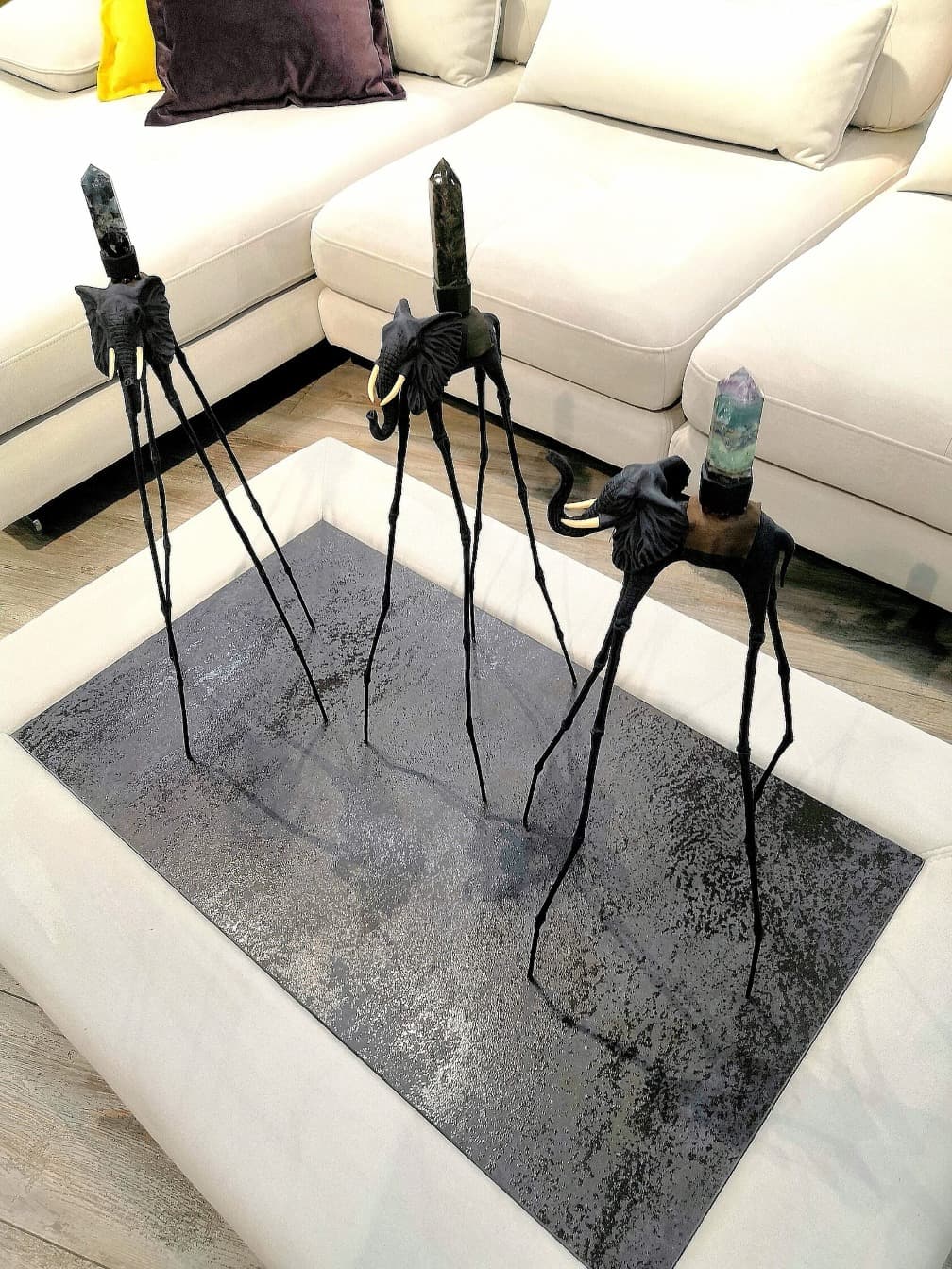 Синие статуэтки слона Дали с натуральными камнями на фоне дивана — декор в стиле Сальвадора Дали