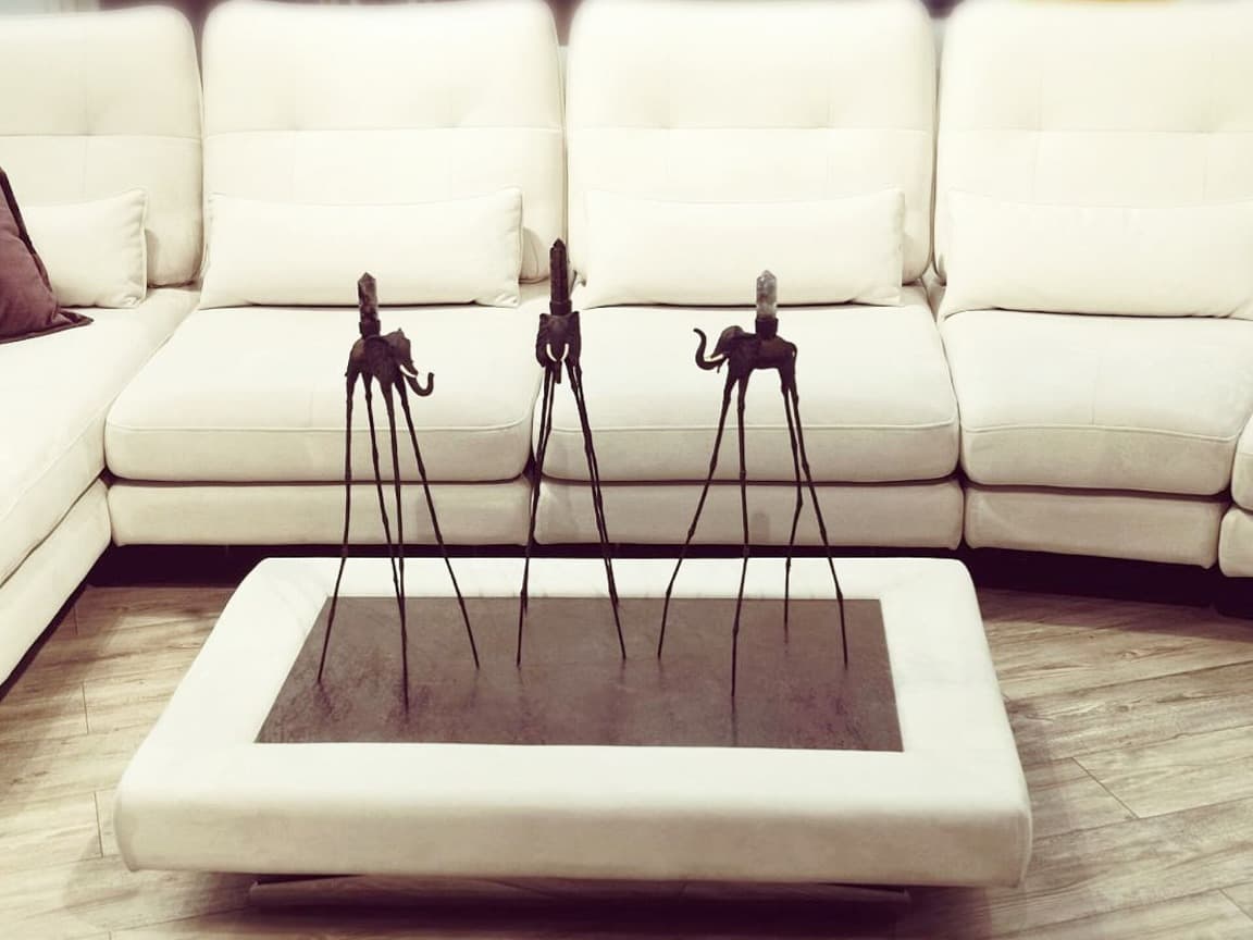 Синие статуэтки слона Дали с натуральными камнями на фоне дивана — декор в стиле Сальвадора Дали