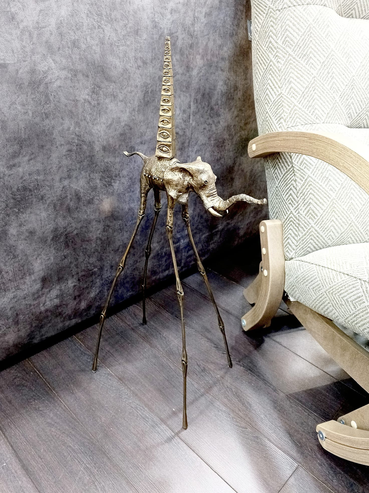 Золотая статуэтка слона Дали с пирамидой рядом с креслом — авторская деталь в современном интерьере